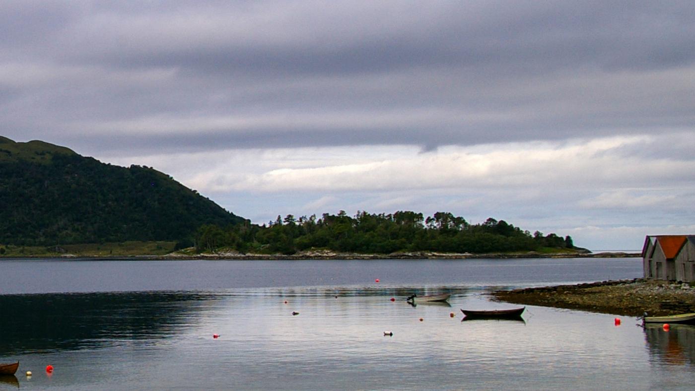 bilde av øy og hav, båt i framgrunnen