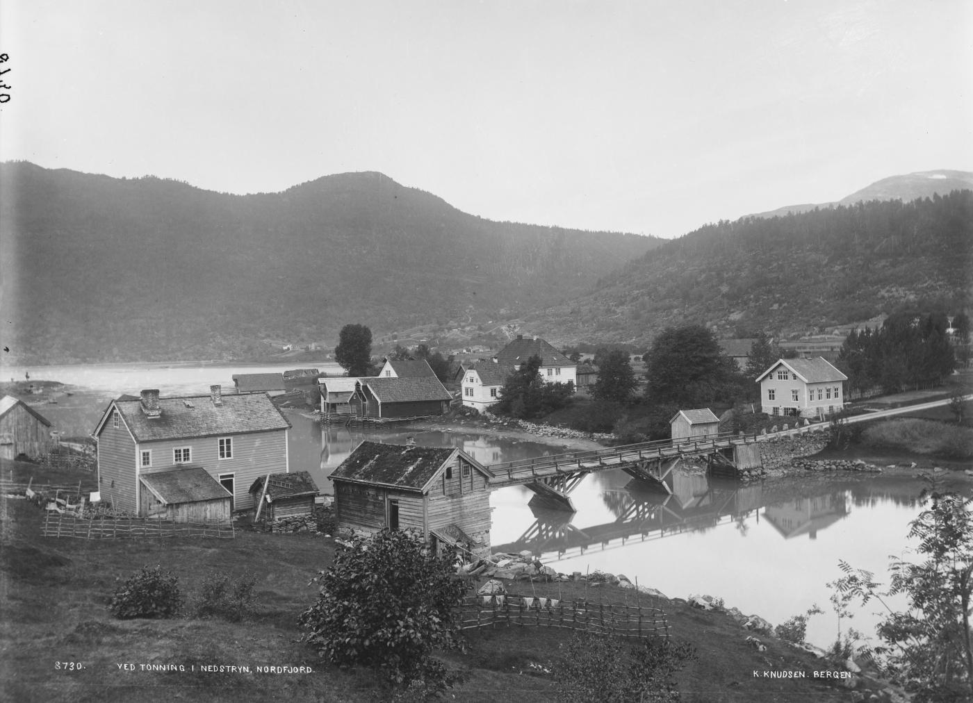 Tonning på slutten av 1800-talet. Brua over elva vart bygd i 1860, før den kom måtte folk skyssast over. Datering 1860-1900. Fotograf K. Knudsen, Bergen. 