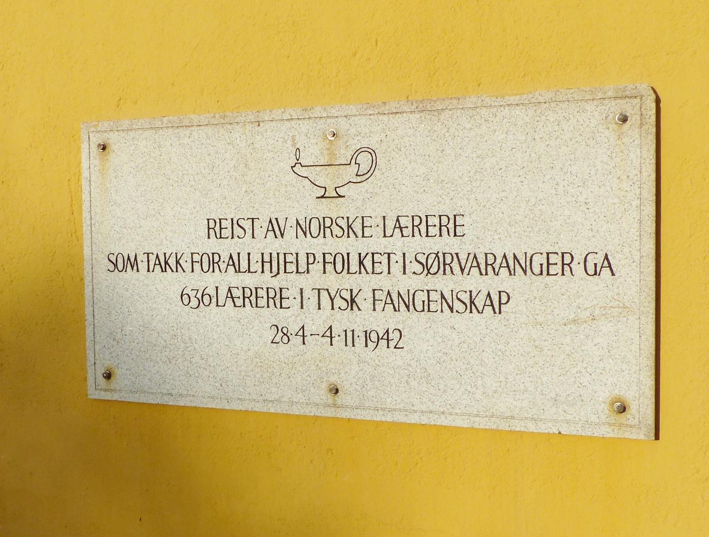 Minneplate på bygning i Kirkenes. Huset var i mange år Kirkenes bibliotek, ei gåve frå norske lærarar som takk til folket i Sør-Varanger for hjelp i fangetida krigsåret 1942. Lærerbiblioteket, heitte det på folkemunne.