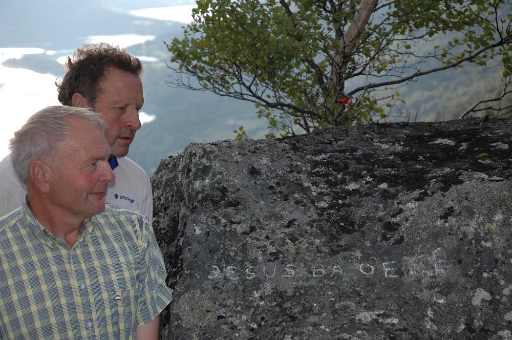 Arne O. Holsen (t.v.) og Reidar Holsen er oldebarn til Ole Andreas Olson. Her ved steinen på Storehåjen som er ein markert haug, til venstre for stølsvegen omlag 10 minutters gange frå stølen. JESUS BA OFTE står det på denne steinen.