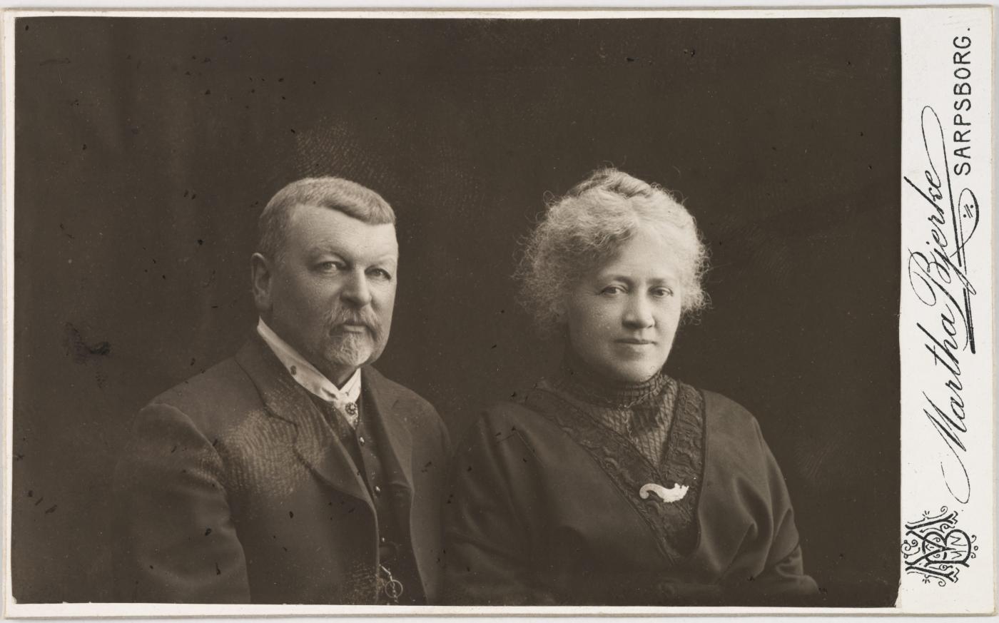 Distriktslege Einar Paasche (1849-1931) og kona Gerhardine Helene Fredrikke Krog, kjend som Dina Krog (1851-1922). Einar Paasche var tilsett som distriktslege i Luster frå 1886 til 1906, men vart i 1906 utnemnd til distriktslege i Sarpsborg. Dette biletet ser ut for å vera teke seinare.