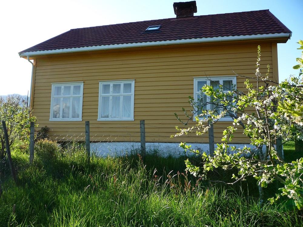 Her ser me gamleskulen i dag, midt mellom ein plommehage og ein eplehage. Dei to vindauga til venstre går inn til skulestova og vindauget til høgre går inn til kammerset. Huset er teke godt vare på. (CC BY-SA 3.0)