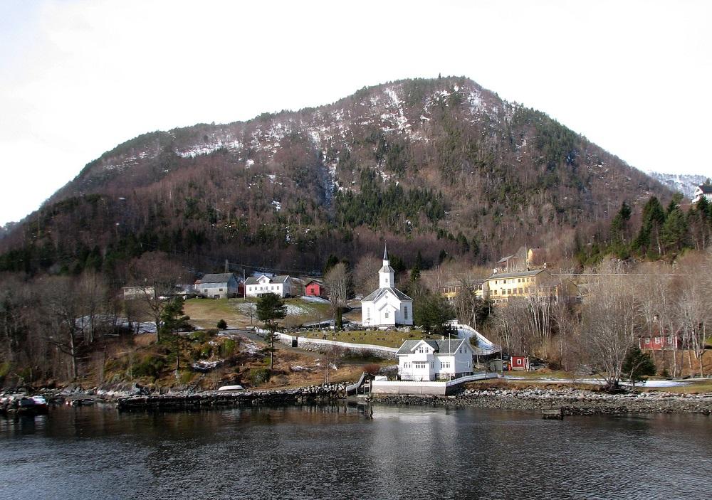 <p>Lavik kyrkje. Sk&aring;sheim skriv om &rdquo;Tinghaugen vest for kyrkja&rdquo; og &rdquo;Lavik-tunet&rdquo;. Biletet viser omr&aring;det vest for kyrkja og tunet p&aring; garden Lavik midt p&aring; biletet.</p>