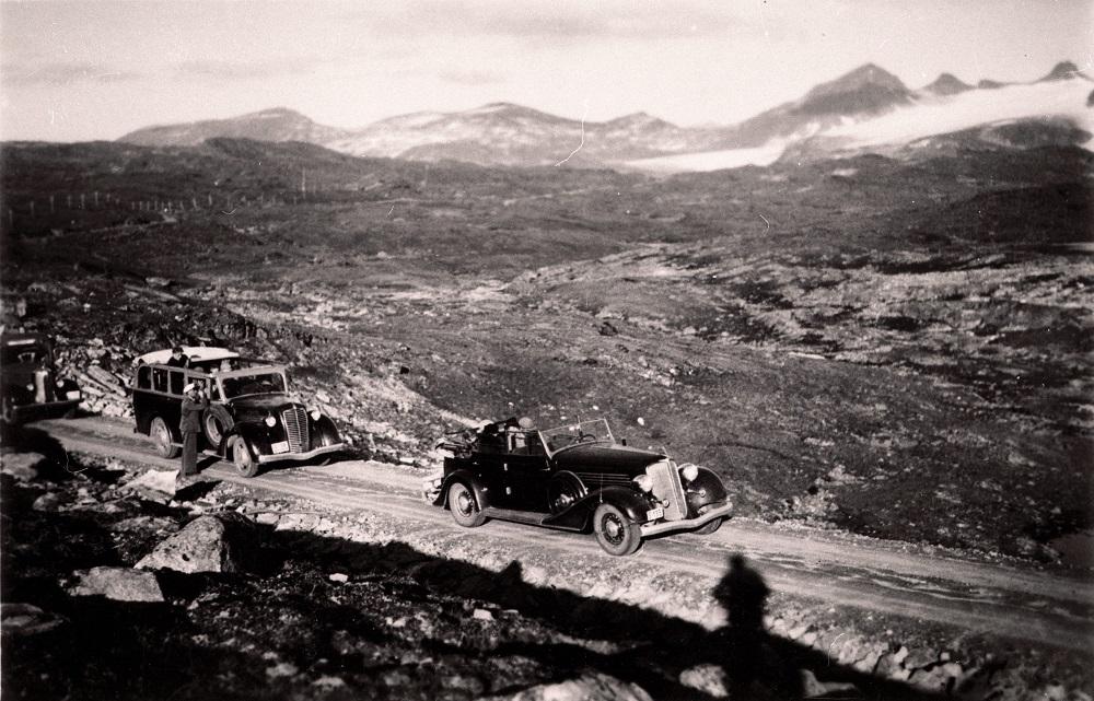 Biletet er frå Sognefjellsvegen sine første dagar. Her er det turkøyring med opne rutevogner. Vegdekket var grus, og køyrebreidda veksla frå 3 m i kostbart terreng til 5 m på parti der ein auke i vegbreidda ikkje påverka kostnadene. I ein kommentar til vegstandarden seier Sogns Avis i 1938, at nedanfor Turtagrø var det eit stykke av vegen som ikkje var vidare godt å køyra, men at det likevel ikkje var verre enn at bilane kunne komma fram. Dette partiet vart utbetra i 1939.
