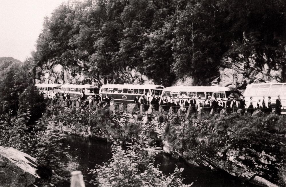 Vegen mellom Dale og Osen vart ikkje offisielt opna før i 1958, men kunne trafikkerast noko tidlegare. Her ser vi fire bussar og passasjerar på veg til ei bygdeungdomslagsstemna i Førde i 1964. 