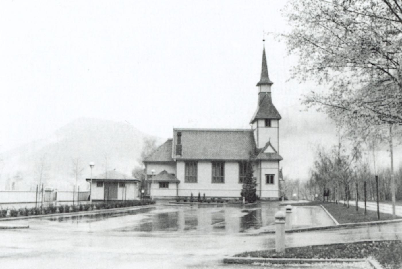 Gaupne kyrkje er teikna av same arkitekt og bygd av same byggmeister som Sæle kyrkje. Ein ser difor lett att dei har mykje til felles. Biletet er teke på ein grå regnvêrsdag.
