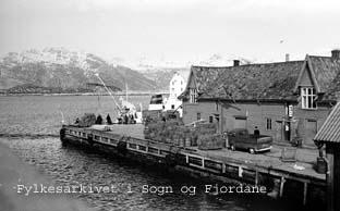 Florø kring 1965. I åra før 1865 opplevde Florø svært sterk vekst i folketalet. Det rike sildefisket gav gode tider. Florø har og makta å halda jamn vekst i næringsliv og folketal. 
Fram gjennom tidene har Florø vore ei av dei viktigaste hamnene i fylket for Fylkesbaatane. Mang slags last har passert over kaiane. Her er vi på Fylkeskaia ein marsdag i 1965. Ei last med for til buskapen på øyane står klar til innlasting. 

