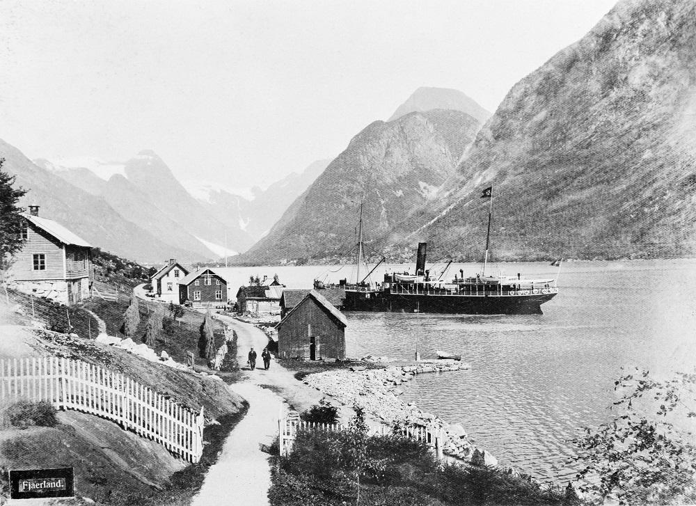 Mundal i Fjærland ein sommardag kring 1900. Dette var sentrum i Fjærland med hotell, butikkar, postopneri og dampskipsekspedisjon. Me ser båten i ferd med å bakka ut frå bryggja.