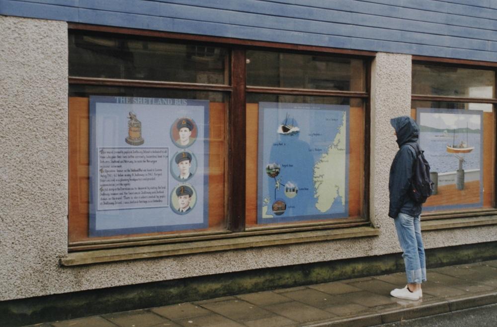 The Shetland Bus-mission, den organiserte trafikken mellom Shetland og Noreg under andre verdskrigen, har stor plass hjå shetlendarane. Desse utstillingsplansjane i hovudgata i Scalloway er laga av grunnskulen i byen. Her studerer Elisabeth Kleppa ei av dei.


