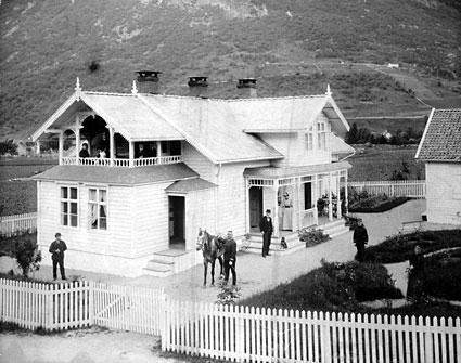 Eldste Øen-huset bygt 1887-88, huset brann ned i 1898. Attmed hesten står  oberstløytnant Solem som leigde huset. Det var eit flott hus med velstelt hage. Endre J. Tryti (1862-1946), som bygde huset, står til venstre. Huset har mange utskjeringar og dreidde stolpar. Det er stakittgjerde rundt heile eigedommen.