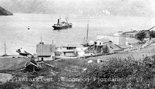 Talkmølla i Framfjorden. Det føregår bygging ved mølla og utpå fjorden ligg ein båt. I huset attmed mølla budde fyrst fabrikkeigar Wilhelm Blauw, sidan Jacob Kjøde. Blauw var ein gründartype som var engasjert i mange industriprosjekt. Etter at Blauw gjekk konkurs i 1925, var det Jacob Kjøde som overtok og dreiv mølla vidare. Ei tid var der 60 arbeidsplassar, medan det i 2000 berre arbeider 3-4 mann ved mølla.