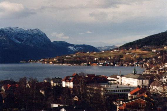 Bilete teke frå Sandane sentrum mot Austrheim. Austrheimsgardane ligg lunt og solrikt til på nordsida inst i Gloppefjorden. Klima og dyrkingstilhøve er av det aller beste vi finn i Nordfjord, og ut frå dette var sjølvsagt området eit godt val for tidleg busetnad og dyrking.
