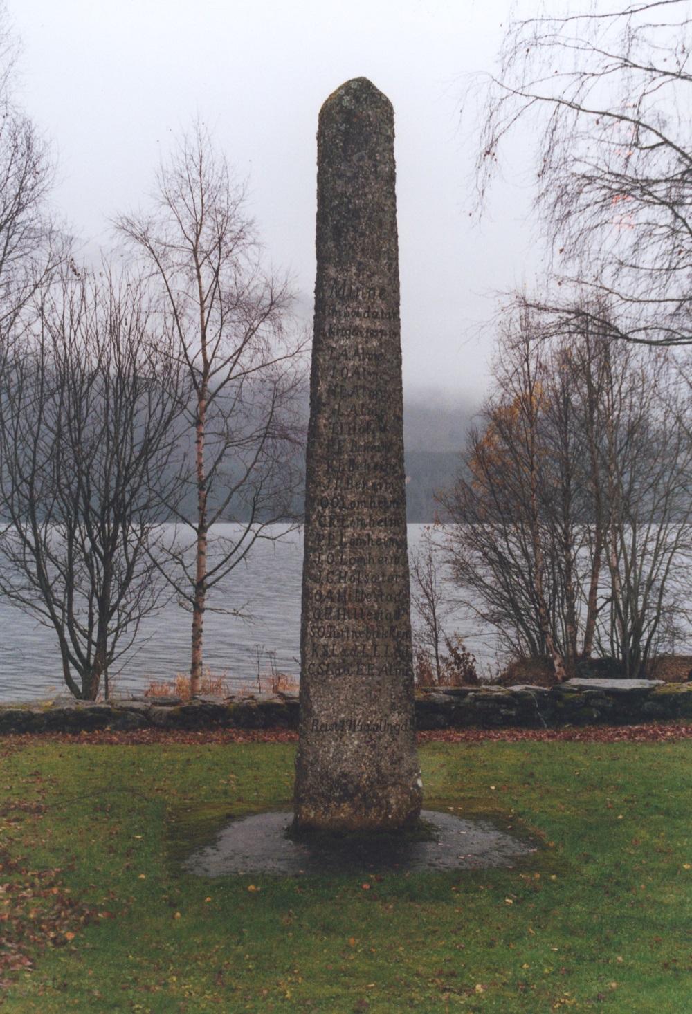 <p>1814-steinen p&aring; Hafslo st&aring;r p&aring; ein open plass ved kyrkja. Han er festa i eit betongfundament. I bakgrunnen Hafslovatnet.</p>