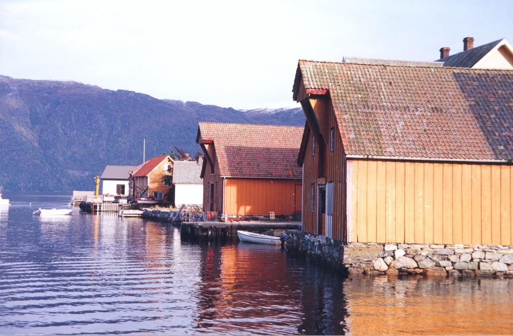 Det maritime bygningsmiljøet på Hestnesøyra. Frå høgre ser vi Josefbuene, deretter følgjer det kvitmåla fryseriet. Tidlegare var det meieri i dette huset. Det oransje huset bak meieriet ligg på området til dampskipskaia, og fungerte som lagerplass for varer som kom eller skulle sendast med rutebåtane. I det kvite huset lengst til venstre heldt Brødrene Eikenes metallstøyperi til. Dette huset er av ny dato.
