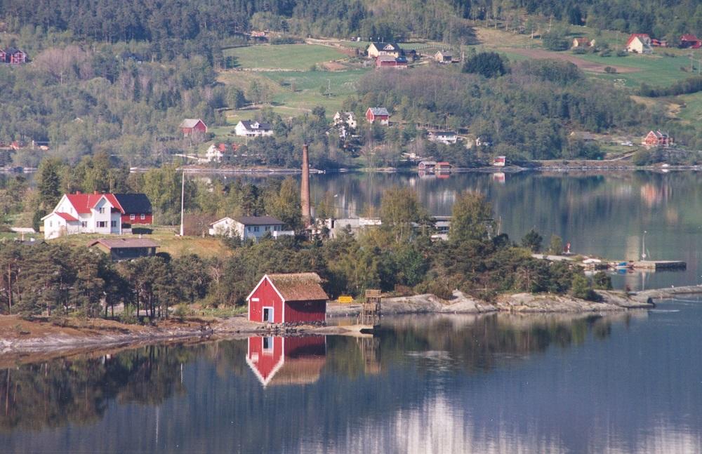 Biletet er teke mot sørvest med Notabua og Selvågane i framgrunnen. Rett bak Notabua, på Elvaneset ser vi den gamle pipa etter tidlegare Evebøfoss fabrikkar på Sandane. I bakgrunnen garden Arnestad som ligg på sørsida i inste del av Gloppefjorden.
