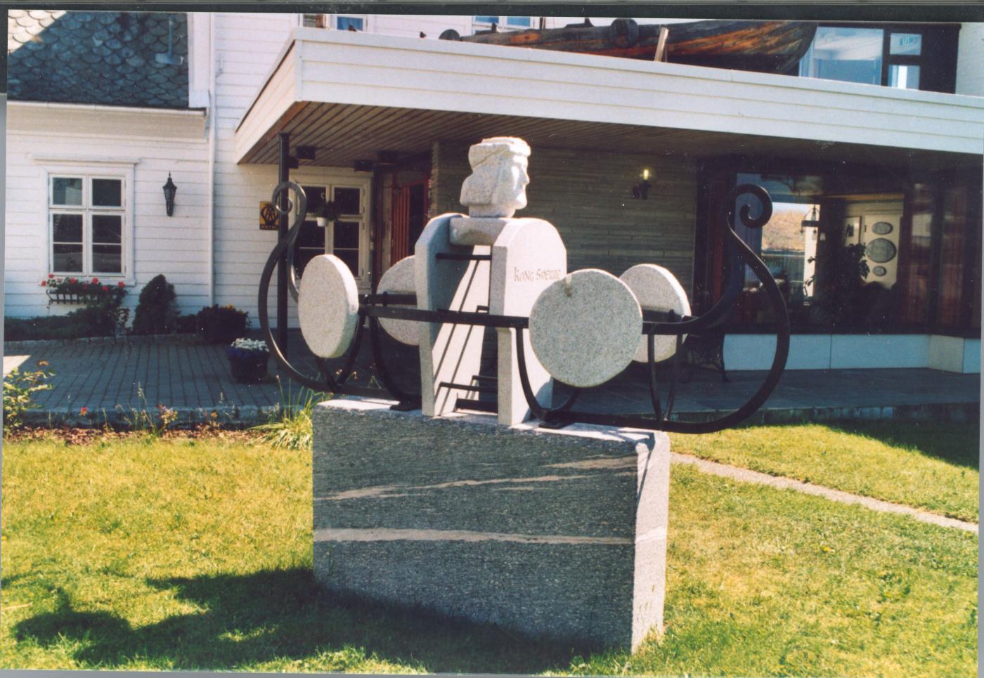 Stig Eikaas sin kong Sverre-skulptur står framfor hovudinngangen av Leikanger Fjordhotell på Leikanger. Skulpturen vart avduka i mai 2002.