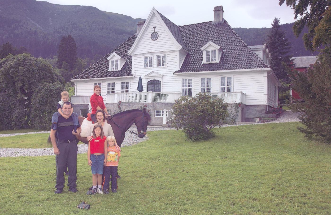 Den gamle futegarden på Askelund slik den ser ut i dag. Kring 1990 var huset byrja å forfalla. I tida som asylmottak vart det sett av midlar til å stoppa forfallet og å få sett huset i stand att. Den negative utviklinga vart snudd. Futegarden er i dag i aktiv bruk. Frode og Anita Høyvik kjøpte eigedomen i 1988. Her står dei framføre futegarden saman med borna Ola (4), Vår Maja (6), Thea (8) og Ina (15).  
