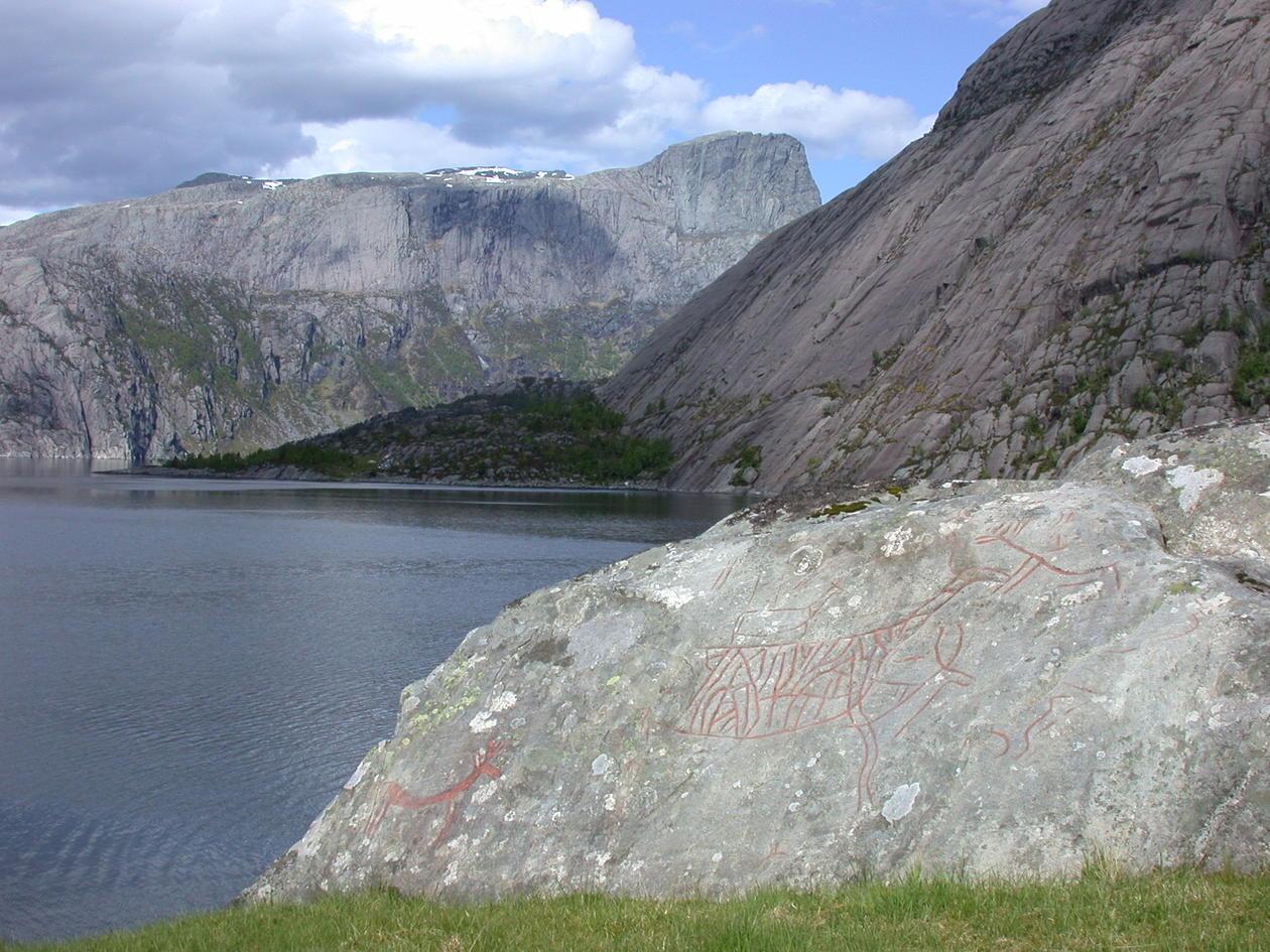 I Vingen inst i  Frøysjøen ligg den største samlinga av bergkunst i Sør-Noreg, til no er det  avdekket over 2200 rissingar. I bakgrunnen siglingsmerke Hornelen som ragar 860 meter over vassyta og er den høgste sjøklippa i Europa. Foto Trond Lødøen, Universitetsmuseet i Bergen.