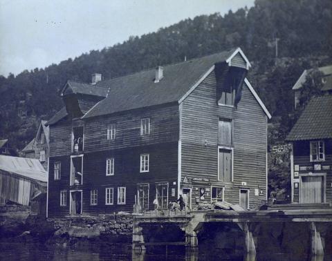Jørgen Ryssdal si bu på Sandane i 1920-åra. Han kjøpte bua hjå Gloppen og Breim Handelsforening. Bygningen fekk tilført ein ekstra etasje
i 1917. I gluggen i andre og tredje etasje står det menn med tønner.
