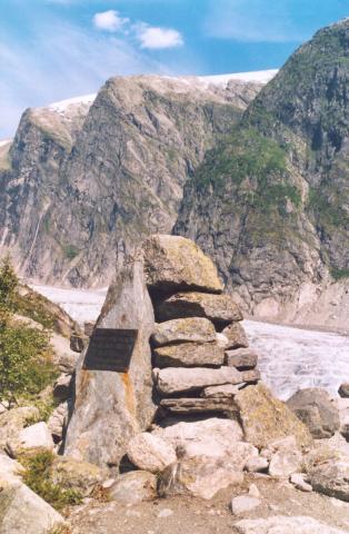 Minnevarden ved Austerdalsbreen. Brearmen kjem ned frå storbreen over i biletet og strekkjer seg heilt ned der dalen gjer ein sving og opnar seg mot ei vid og flat slette i dalen.