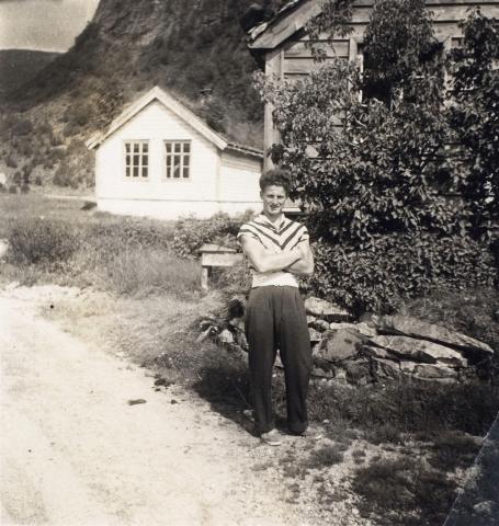 Skulehuset der det stod opphavleg, på garden Guddal, i daglegtale kalla Øyra. Biletet er teke kring 1955 og det er Erling Guddal som er fotografert.