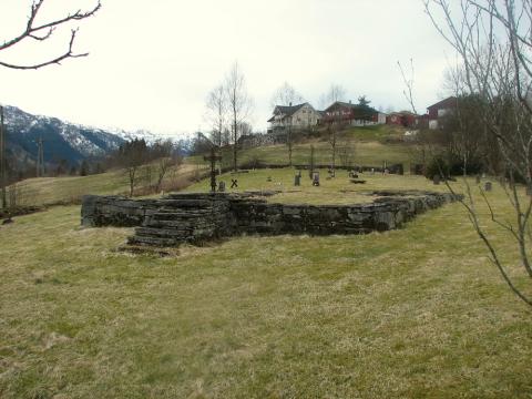 Bygstad gamle kyrkjegard 2008, med tufta der kyrkja stod til 1939. Det var her Lars Sjurson Osen vart gravlagd 27. juni 1903. Hovudinngangen til kyrkja var i motsett ende av av trappa i framgrunnen på på biletet.