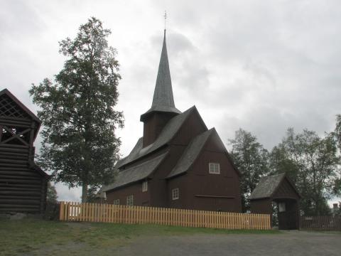 Hegge kyrkje i Øystre Slidre. Det går stakittgjerde ut frå hovudporten. Minnesteinen over Peder A. Mundal stod tidlegare "rett innom" hovudporten. No er han sett tilsides ved stakittgjerdet på oppsida (venstre) av kyrkja.