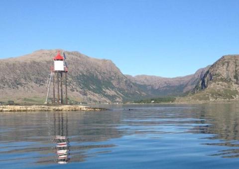 Olaskjeret fyrlykt med Botnane i bakgrunnen. Det var litt sørom og innom dette skjeret dampbåten «Engøy» gjekk på ei mine og sokk 6. mars 1943. I Nordbotten (som viser bak jernstengene) var folk samla i gravferd då ulukka hende. Kort tid etter hendinga fossrodde folk ut for å sjå om det trongst hjelp.