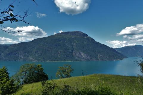 Lindeflaten, med utsyn mot nordsida av Lustrafjorden, garden ytre Eikjo ved sjøen, under fjellpartiet Molden.