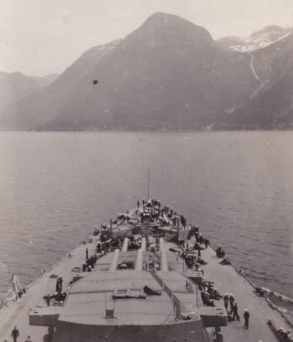 Biletet viser slagskipet på veg inn Hardangerfjorden med kurs mot ein stad mellom Kinsarvik og Ringøy. Elva forut er Teismeelva.