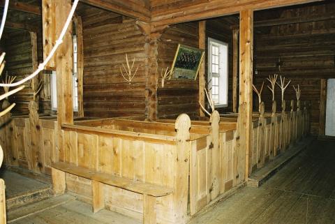 Kyrkjebenkene i ein av krossarmane. Dei innebygde faste benkene stammar truleg frå stavkyrkja som stod fram til 1746. Dei har rike utskjeringar, og nokre har namn, initialar og årstal. På kyrkjestolane er det festa hatteknaggar av avborka ungbjørketoppar. Vi ser også litt av tauet til kyrkjeklokkene.
