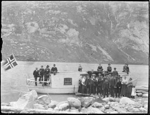 Den første motorbåten på Veitastrondsvatnet kom i 1905. Båten heitte frå først av "Strendingen", men folk sa etter kvart oftast 'Motoren'. Per O. Nes var maskinist, og Augund Skagen skippar. Her ser vi båten klar for avgang nedover vatnet frå Nes. Det var fleire bryggjer langs vatnet og ved Soget var endestasjonen. 'Motoren' gjekk frå Strondi (Nes) kl 8.00 om morgonen og brukte rundt to timar til Soget. 

 