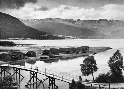 Storebrua over Storeelva (Gloppenelva), fotografert ein gong i 1930-åra. Det var vegen mellom Sandane og Ryssdal som utløyste kravet om bru. Brua vart bygd rundt 1887. Ho var høg på midten av omsyn til båtferdsla. Det heiter seg at han "Eljas i Elvene" kravde at brua måtte vera så høg at "han kunne seile til Kirke hver eneste søndag". I 1939 kom det ny bru.