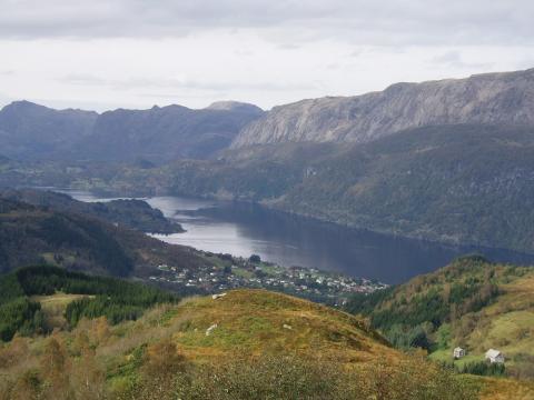 På nordsida av Dalsfjorden kan ein så vidt skimta "geitestien," som den uferdige vegen frå Eikenes til Otterstein vert kalla. Bildet er teke frå Grøneholten som ligg sør-aust for Dale. Vi ser ferjeleiet på Eikenes til venstre på bildet.

