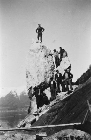 Vegarbeid ved Vestrheimsanden på anlegget Leikanger-Hella i 1954. Det var ein god del sprengjingsarbeid mellom Eitorn og Hella. Etter ei salve salva reiste denne steinen seg på ende. I bakgrunnen ser vi Balestrandsfjella. 