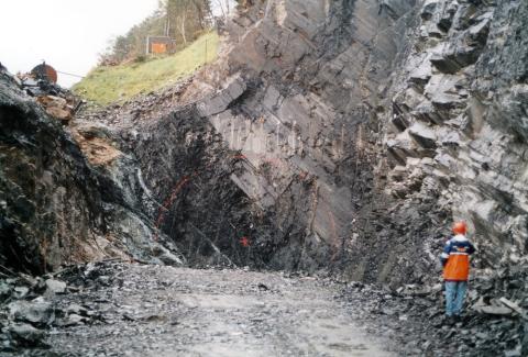 Tunnelpåhogget på Klubben er her oppmerka, 8. september 1999. Fjellet var svært lagdelt og oppknust. Ein kan sjå ei sone med talk til venstre. Dette er ein bergart som skaper vanskar i tunnelarbeid. Det dårlege fjellet i starten reiste tvil om grunntilhøva var gode nok. Vegdirektoratet ville ha fleire grunnundersøkingar, men arbeidet gjekk likevel som normalt.