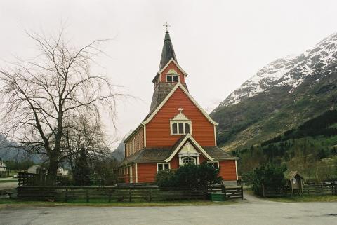 Den raudmåla kyrkja i Olden er svært elegant utforma, med sideskip og takryttar tydeleg inspirert av stavkyrkjestilen.