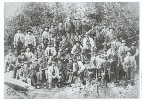 Vegen gjennom Haukåsgjelet vart bygd i åra 1889-1891. Her er vegarbeidarar fotograferte i samband med fint besøk, vegdirektør Hans Hagerup Krag (med krossreim i midten) og amtsingeniør Christopher Engebreth Borch (med klokkekjede i midten til høgre).
Sju mann held på ein reiskap, og elles er biletet interessant med omsyn til arbeidsklede.