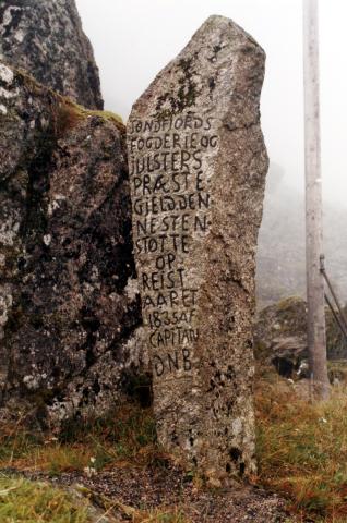 Steinen vart reist i 1835. Denne sida vender oppover/sørover mot "Søndfjords fogderie og Julsters præstegjeld." 