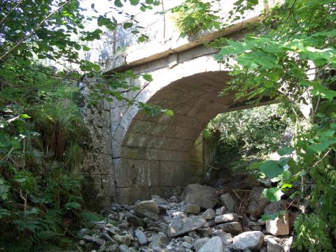 I 1914 vart det bygd ny veg frå garden Flesje og innover mot Balestrand sentrum. Den avløyste den gamle vegen som gjekk frå gardstun til gardstun. Det måtte byggjast ny bru over Tuselv. Då sette ein opp denne vakre kvelvingsbrua, Tue bru. Den gamle vegen frå 1914 er omlagd og ombygd fleire gonger.