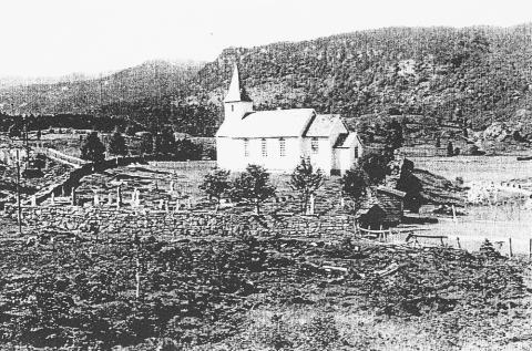 Guddal kyrkje på garden Engen i 1943. Kyrkja står orientert aust-vest. Det var på sørsida av kyrkja dei fyrst på 1900-talet fann likkister i eit myrområde.




