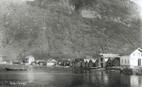 Slik såg den gamle naustrekkja ut. Få av desse nausta står att i 1999. Men nokre står att og er med å gje Vikøyri det særpreget det har. Riksvegen vart lagd mellom fjorden og nausta, slik at den direkte kontakten til sjøen vart broten. Det store toetasjes bygget til venstre var gamle Frelsesarme-bygget i Vik.