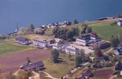 Nordfjord folkehøgskule ligg vakkert til på den vestre delen av Vereidesletta. I framgrunnen syner tre store gravhaugar.
