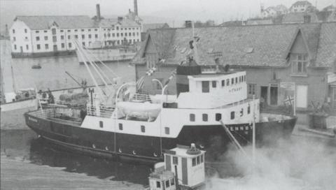 Fylkeskaia sist på 1950-talet. Den nye lokalbåten "Hennøy" - bygd i 1957 - ligg på vestsida av kaia. Døra til Hamnekafeen - Haffen - ser vi like i framkant av overbygget på båten. Kafeen var i andre høgda i sørenden av bygningen, med utsikt til trafikken i Torggata og Strandgata, og mot hamna gjennom vindauga i spissarka over inngangen. I bakgrunnen ser vi Hermetikkfabrikken.