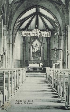 Sør-Vågsøy kyrkje 17. mai 1914. Frå markeringa av 100-års jubileet for 17. mai 1814. Over altertavla heng eit banner med "Einige og tru til Dovre fell".
