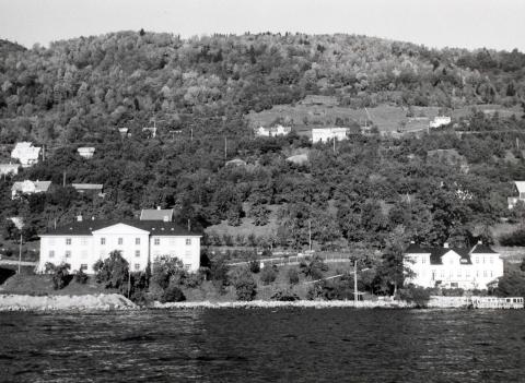 Sorenskrivargarden og Tinghuset (teke i bruk 1939), slik dei såg ut frå sjøen kring 1950. Det er hage rundt sorenskrivarbygningen og bryggje, og veg inn til begge husa frå riksvegen. Det store treet attmed venstre fløyen er eit valnøtt-tre, som måtte bort då det vart bygt veg ut til tinghusa nedom sorenskrivargarden. Det var óg nære på at Skrivareika vart nedhoggen.