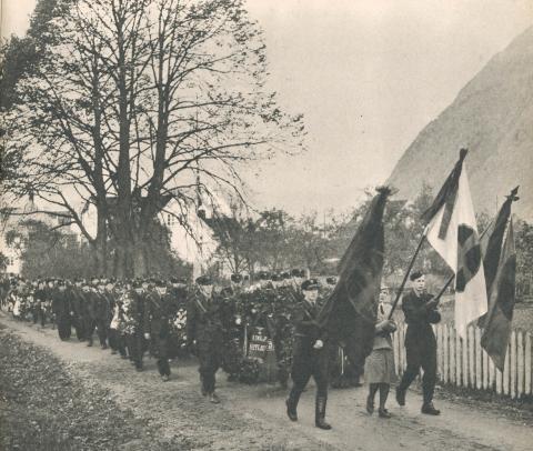 Urnene på veg til den siste kvilestaden på familiegravstaden ved Hopperstad stavkyrkje. Fremst i prosesjonen går ei borg med tre solkorsbanner. På ei sløyfe står ADOLF HITLER og hakekorset.