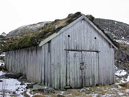 Eitt av nausta på landingsplassen sett frå sjøsida. Lengst til venstre på biletet skimtar vi kapellet på Kråkenes.