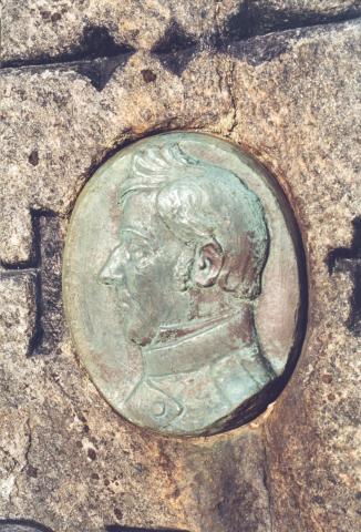 Medaljongen i bronse er festa mellom fødselsåret og dødsåret. Han er laga av modellør Torvald Olsen, Bergen, etter eit silhuettbilete av generalmajor Holck.